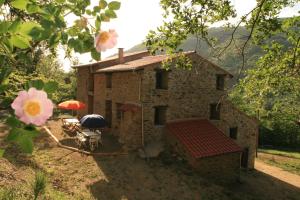 ein kleines Steinhaus mit einem Sonnenschirm und einer Terrasse in der Unterkunft Chambres d'hôtes Mas La Tardosse in Prats-de-Mollo-la-Preste