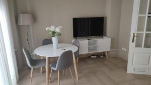 a white dining room table with chairs and a television at Saavedra Free Parking Cordoba Center in Córdoba