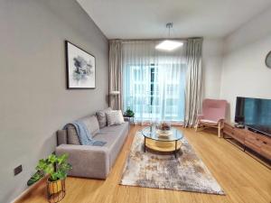 a living room with a couch and a tv at White Sage - Fountain View Stylish Apt With Spacious Terrace in Dubai