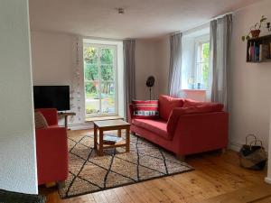 a living room with two red couches and a television at Gemütliches Ferienhaus im Extertal/ Lippe in Extertal
