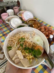 a person holding a bowl of food with noodles at DD Grand Hotel in Seka