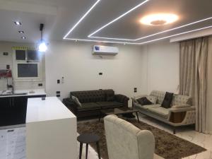 a living room with two couches and a kitchen at شقة فندقية بغرفتين قرب مول مصر وميدان جهينة families only in Sheikh Zayed