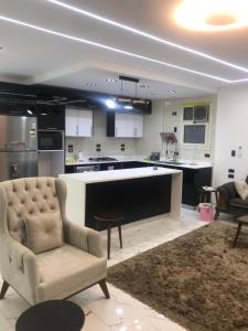 a kitchen with a couch and a chair in a room at شقة فندقية بغرفتين قرب مول مصر وميدان جهينة families only in Sheikh Zayed