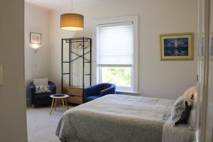 a bedroom with a bed, chair and a window at Windarra on High in Launceston