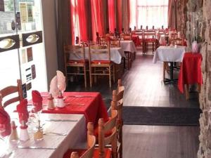 アランソンにあるHôtel Le Hussardの赤いテーブルクロスのテーブルと椅子が備わるレストラン