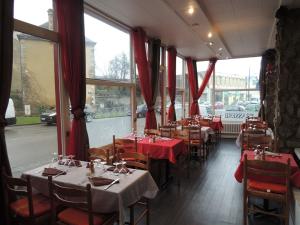 アランソンにあるHôtel Le Hussardのテーブルと椅子、赤いカーテンが備わるレストラン