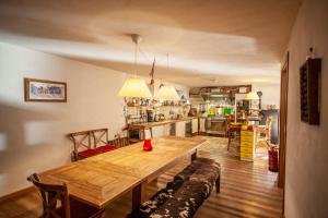 a dining room with a wooden table and a kitchen at Maison Le Champ B&B Questa casa non è un albergo in La Salle