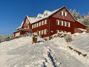 a person standing in the snow in front of a red building at Penzion Pod lesem in Pec pod Sněžkou