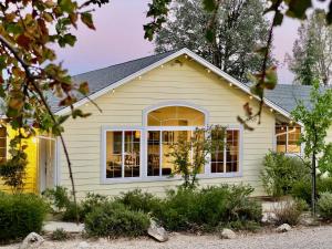 a house with yellow siding and a window at Glamour Mountain Getaway by Casa Oso with views and spa in Oakhurst