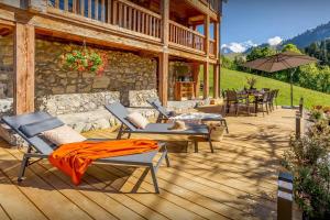 a wooden deck with chairs and tables on a house at Chalet Argali - OVO Network in Le Grand-Bornand