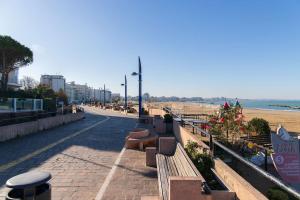 a row of benches on a sidewalk next to the beach at Pascoli Home a Cattolica Centro Mare by Yohome in Cattolica