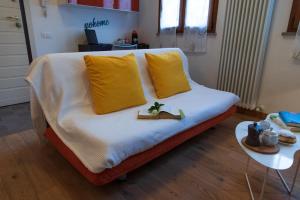 un divano con 2 cuscini gialli e un tavolo di Pascoli Home a Cattolica Centro Mare by Yohome a Cattolica