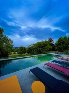 a swimming pool with four lounge chairs at Holiday Home Les Plachettes in Flobecq