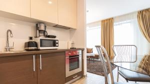 a kitchen with a microwave and a table with chairs at Cold Mountain Apartment in Silver Mountain Resort in Poiana Brasov