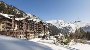 a hotel in the snow with snow covered mountains at Appartement Premium à Flaine, altitude 1740 m, 8 à 10 personnes, au pied des pistes, piscine, jacuzzi, sauna, hammam et salle de sport in Flaine