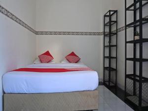 um quarto com uma cama branca e almofadas vermelhas em OYO 91900 Wisma Amrach em Watampone