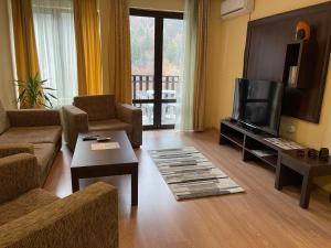 a living room with a couch and a television at Мия 2 Спа хотел Свети Спас in Velingrad