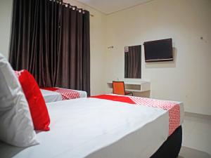 a hotel room with two beds and a tv at OYO 91900 Wisma Amrach in Watampone