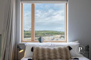 a bedroom with a large window with a view of a beach at Primero Apartments - Hayle Villas in Hayle