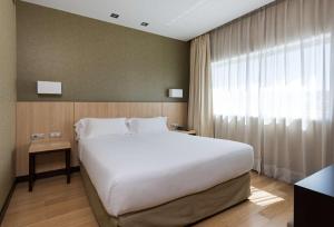 a bedroom with a large white bed and a window at NH Madrid Ribera del Manzanares in Madrid