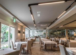 a restaurant with white tables and chairs and windows at Bellettini Hotel in Milano Marittima