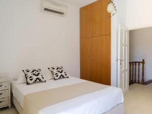 ElefternaにあるVilla Nikolaosの白いベッドと木製キャビネット付きのベッドルーム1室が備わります。