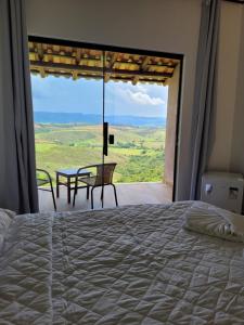 a bedroom with a bed and a table and a view at Pousada Colina da Canastra in São Roque de Minas