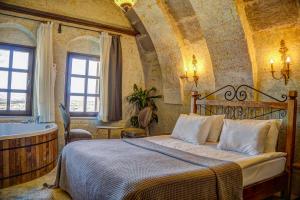 a bedroom with a bed and a tub in a room at Karma Suites Cappadocia in Uchisar