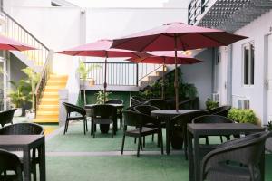 um pátio exterior com mesas, cadeiras e guarda-sóis em Grand Peninsula Suites em Balanga
