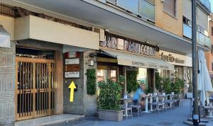 un restaurante con un cartel de flecha amarilla delante de él en Aurelio Deluxe Rooms, en Roma