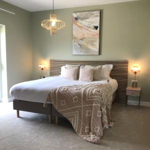 a bedroom with a large bed and a chandelier at Mallard Cottage, Ashlin Farm Barns in Lincoln