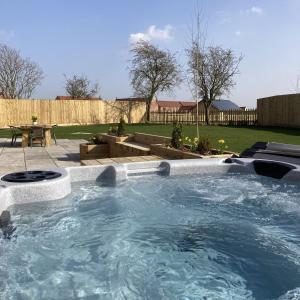 una grande vasca idromassaggio in un cortile con patio di Blue Iris Cottage, Ashlin Farm Barns a Lincoln