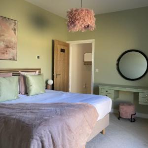 1 dormitorio con 1 cama grande y espejo en Blue Iris Cottage, Ashlin Farm Barns en Lincoln