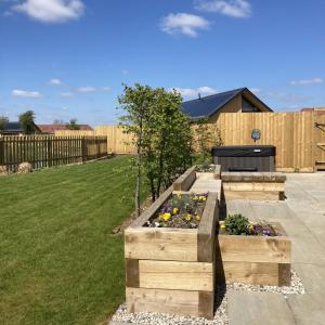 a garden with three wooden boxes with flowers at Water Lily Cottage, Ashlin Farm Barns in Lincoln