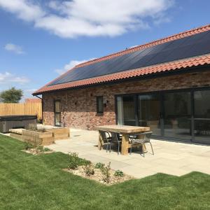 un patio avec une table et un bâtiment doté de panneaux solaires dans l'établissement Castle Hill Barn, Ashlin Farm Barns, à Lincoln
