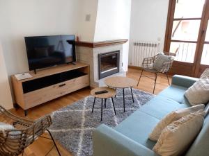 a living room with a blue couch and a tv at BPIRINEOS-Parque Los Tilos 2 in Benasque
