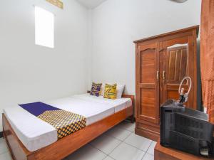 1 dormitorio pequeño con 1 cama y TV en SPOT ON 91935 Hellena Guesthouse, en Demak