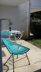 una silla azul junto a una mesa y un patio en SUPERBE APPART AVEC JARDIN ET PISCINE, en Cambo-les-Bains