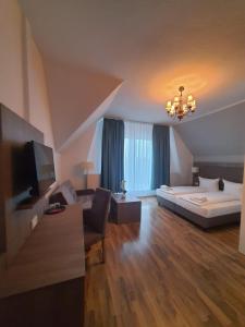 ein Hotelzimmer mit einem Bett, einem Sofa und einem TV in der Unterkunft Hotel Knöpel in Wismar