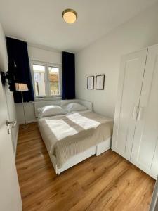 Schlafzimmer mit einem weißen Bett und Holzboden in der Unterkunft Ferienwohnung Freude am Kurpark in Bad Neuenahr-Ahrweiler