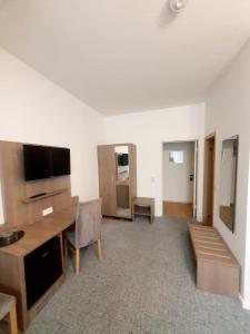 a living room with a desk and a tv at Hotel Knöpel in Wismar