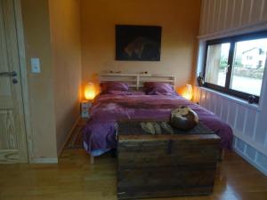 um quarto com uma cama com lençóis roxos e uma janela em Villa Angela, appartement 3 chambres em Ovifat