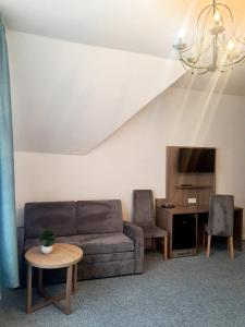 ein Wohnzimmer mit einem Sofa, einem Tisch und einem TV in der Unterkunft Hotel Knöpel in Wismar