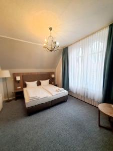 a bedroom with a bed and a chandelier at Hotel Knöpel in Wismar