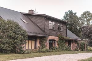 ein Haus mit einem schwarzen Dach und einem Hof in der Unterkunft Viesu nams “Bauļi” in Ventspils