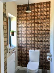 uma casa de banho com um WC e uma parede de tijolos em Meadowsweet Barn, Ashlin Farm Barns em Lincoln