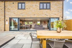 a brick house with a patio with a table and chairs at The Elms, Ashlin Farm Barns in Lincoln