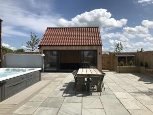 un patio con tavolo, sedie e vasca idromassaggio di The Hazels, Ashlin Farm Barns a Lincoln Altre 7 foto
