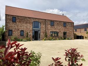 an external view of a brick house with a large yard at The Pines, Ashlin Farm Barns in Lincoln