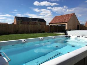 einen Whirlpool im Hinterhof mit einem Zaun in der Unterkunft The Willows, Ashlin Farm Barns in Lincoln